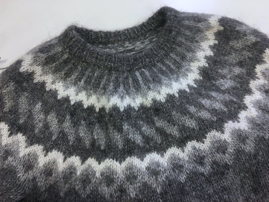 Close view of the yoke of a gray wool sweater knit in a white and charcoal Icelandic pattern.