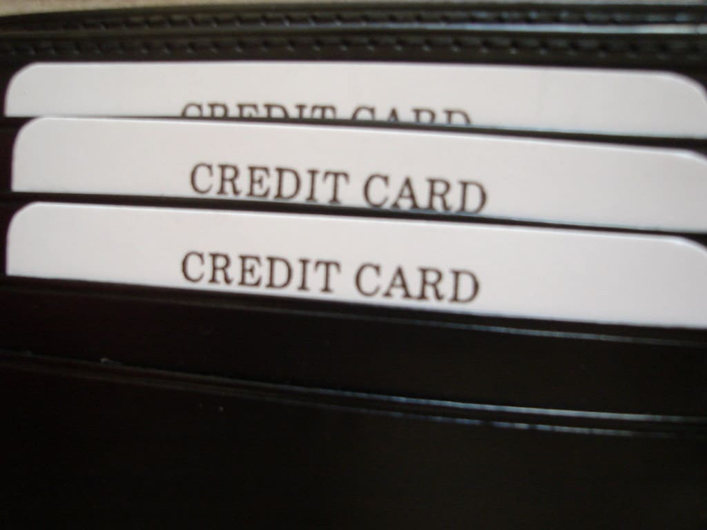 Close view of three plain white cards marked "Credit Card" tucked into the slots of a black wallet.